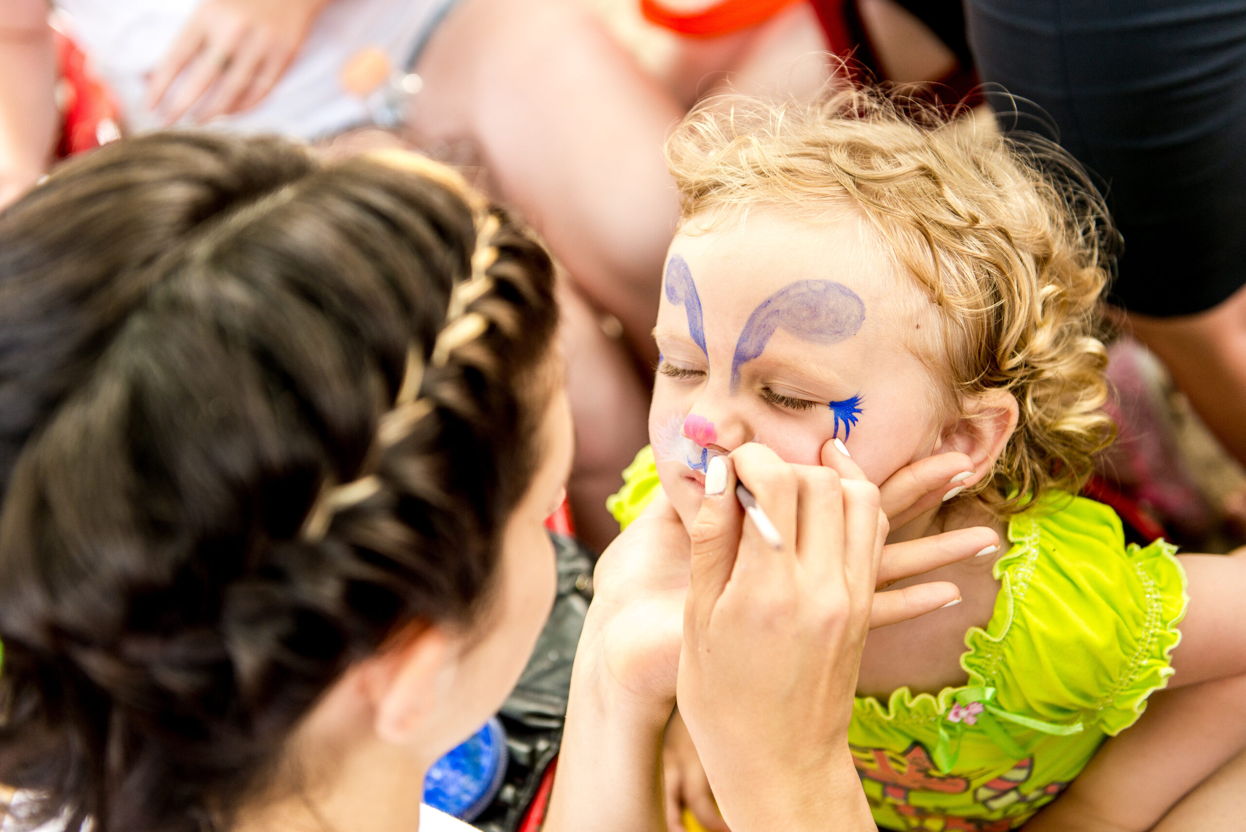 woman painting face of kid outdoors. baby face painting